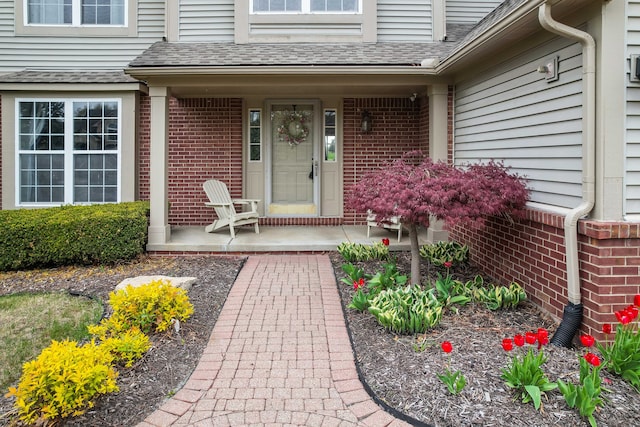 2435 Ivy Hill Dr, Commerce Twp, MI 48382 - doorway to property featuring a shingled roof, a porch, and brick siding