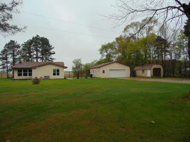 view of green lawn with a detached garage and an outdoor structure