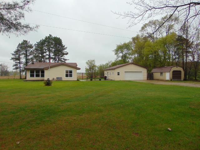 view of grassy yard with a detached garage, an outdoor structure, and a storage unit