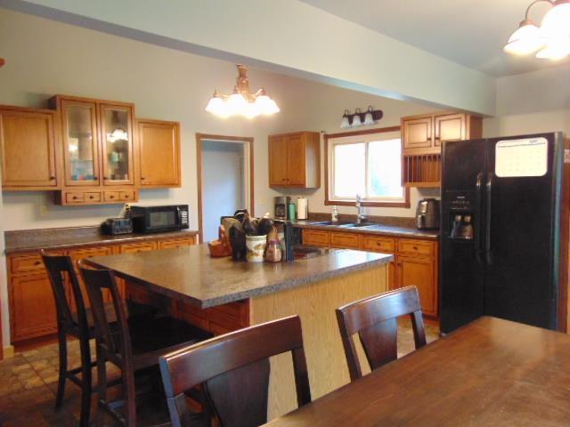 kitchen featuring black appliances, a chandelier, a sink, a center island, and a kitchen breakfast bar