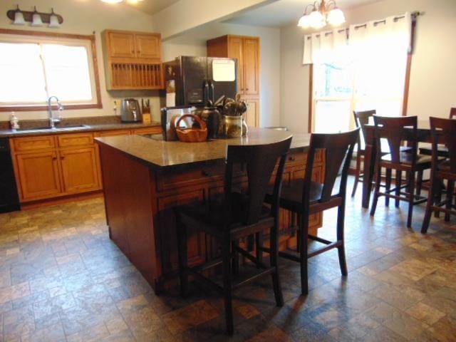 kitchen featuring fridge, a sink, stone finish floors, a center island, and a breakfast bar