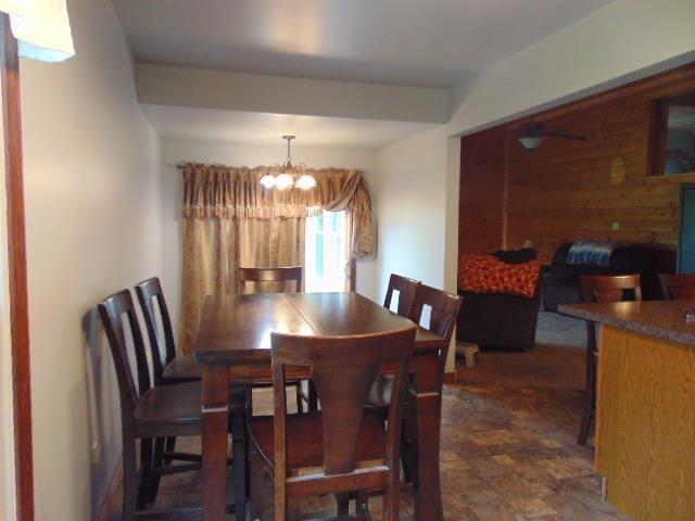 dining space with a chandelier and wood walls