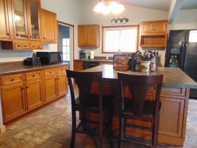 kitchen featuring black appliances, plenty of natural light, a chandelier, lofted ceiling, and a center island