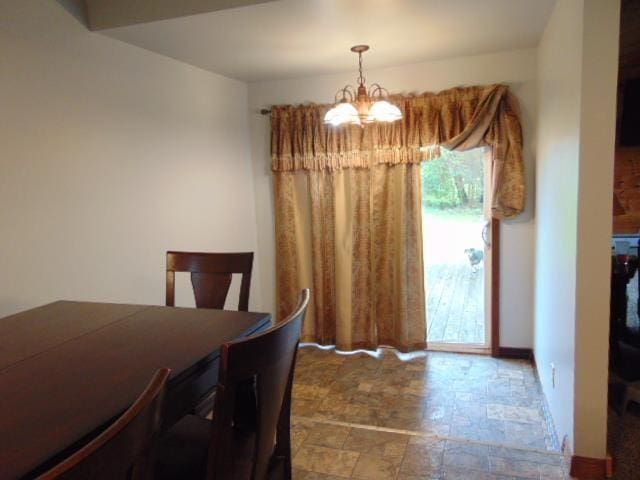dining space featuring a chandelier, stone finish floors, and baseboards