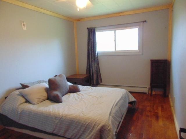 bedroom with a baseboard radiator, wood finished floors, and ceiling fan