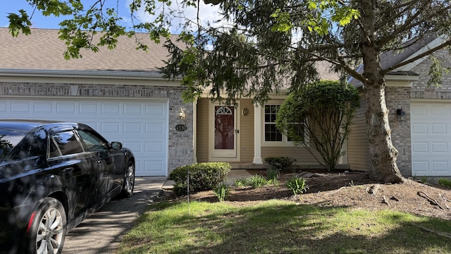 ranch-style home with roof with shingles, an attached garage, and brick siding