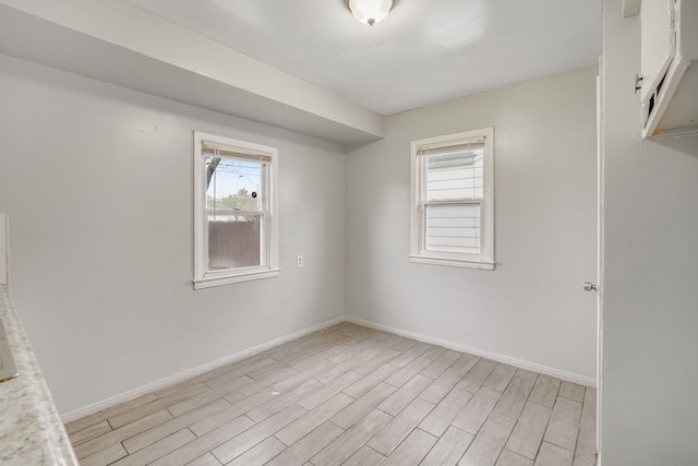 spare room featuring light wood finished floors and baseboards