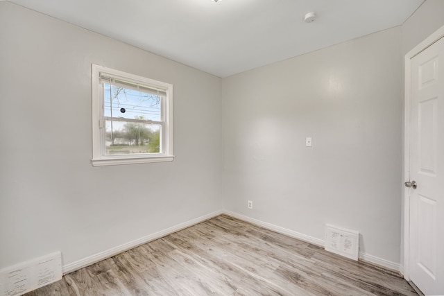 spare room featuring light wood finished floors, baseboards, and a smoke detector