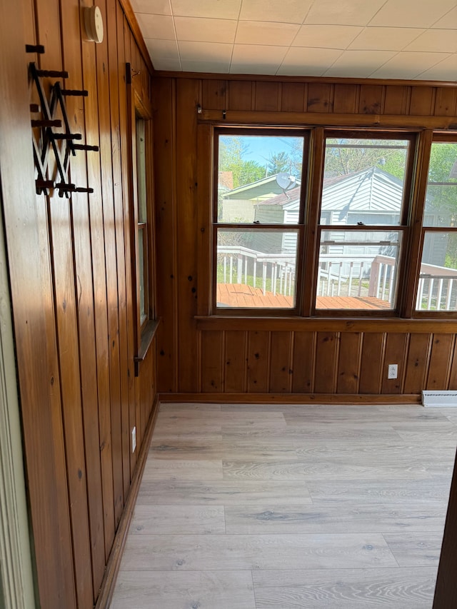 609 Buckingham Ave, Flint, MI 48507 - empty room featuring light wood finished floors, wooden walls, plenty of natural light, and a baseboard radiator