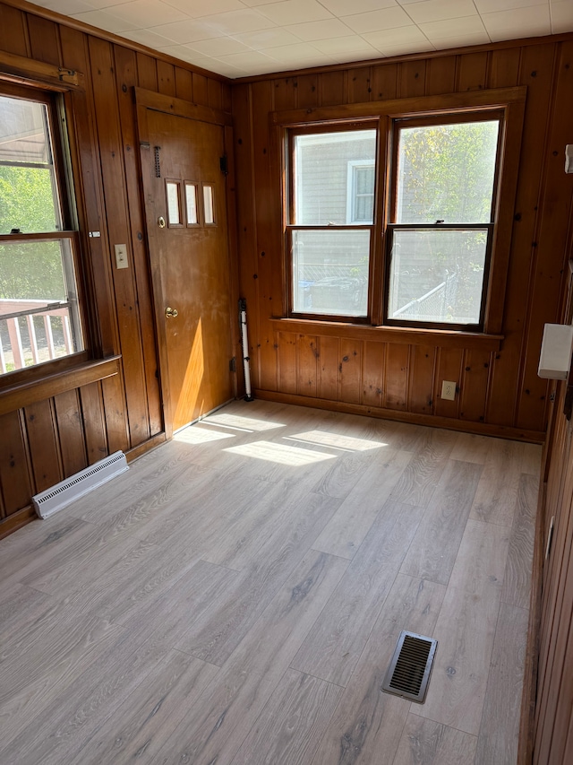 609 Buckingham Ave, Flint, MI 48507 - unfurnished room with light wood-style flooring, healthy amount of natural light, wooden walls, and a baseboard heating unit