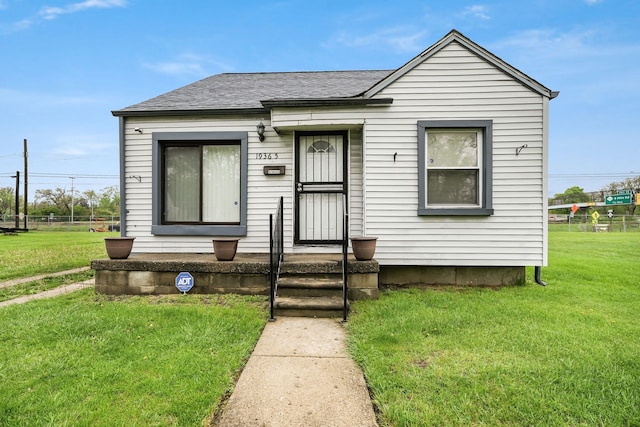 view of front of property featuring a front lawn and a shingled roof