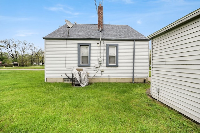 rear view of property featuring a yard and a shingled roof