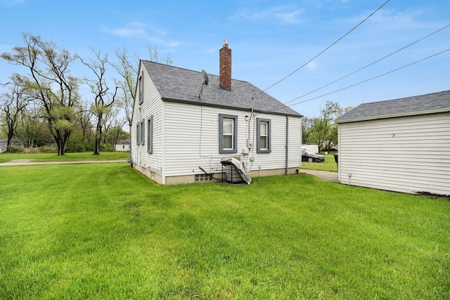 rear view of property with a chimney, a lawn, and roof with shingles