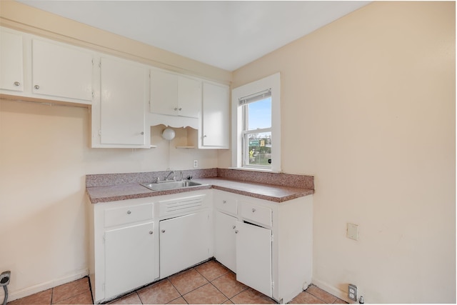kitchen featuring a sink, white cabinetry, light tile patterned floors, and baseboards