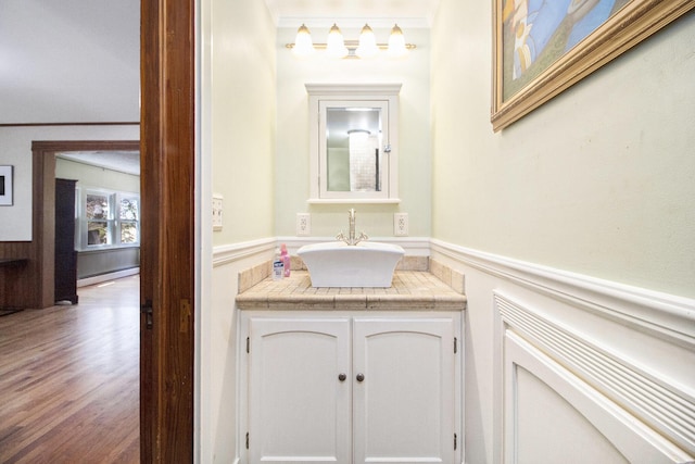 bathroom with wainscoting, vanity, ornamental molding, a baseboard heating unit, and wood finished floors