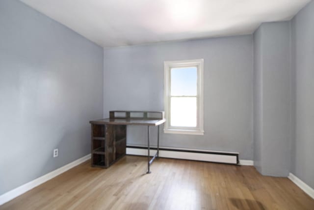 office area featuring a baseboard heating unit, wood finished floors, and baseboards