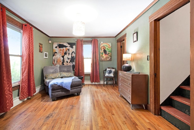 sitting room featuring wood finished floors, ornamental molding, baseboards, healthy amount of natural light, and stairway