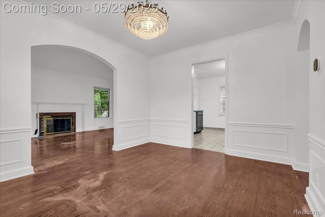 4800 Bishop St, Detroit, MI 48224 - unfurnished living room featuring arched walkways, a decorative wall, wood finished floors, ornamental molding, and a chandelier