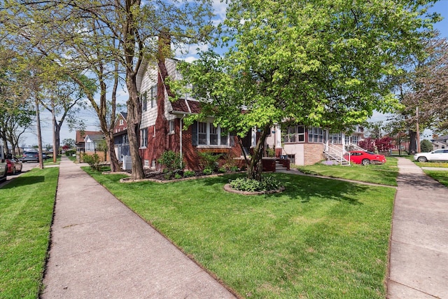 view of front of property featuring a front lawn, a chimney, and brick siding