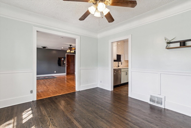 spare room with dark wood finished floors, visible vents, a ceiling fan, and a textured ceiling