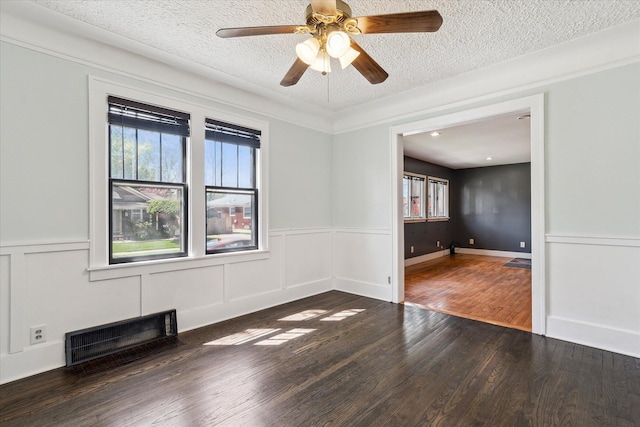 empty room with a textured ceiling, plenty of natural light, and wood finished floors
