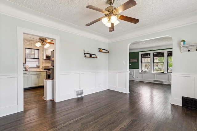 interior space featuring ceiling fan, a textured ceiling, visible vents, and arched walkways