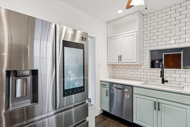 kitchen with a sink, tasteful backsplash, dark wood-style flooring, light countertops, and appliances with stainless steel finishes