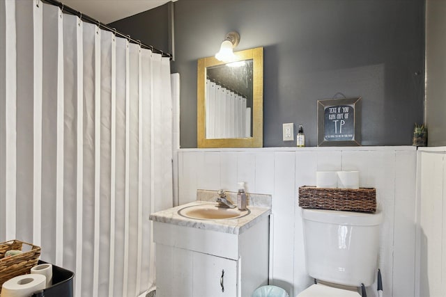 full bath featuring a wainscoted wall, toilet, and vanity