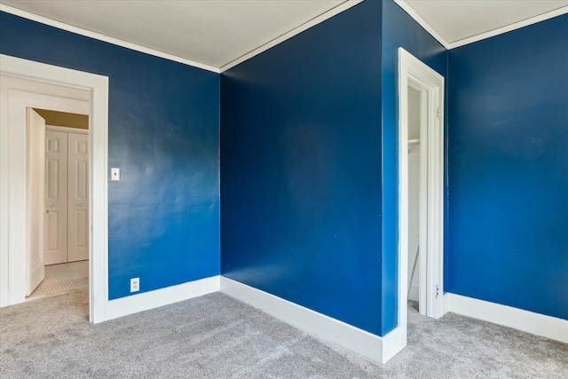 empty room featuring crown molding, carpet flooring, and baseboards