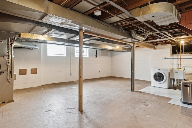 below grade area featuring washer / dryer, heating unit, and a sink