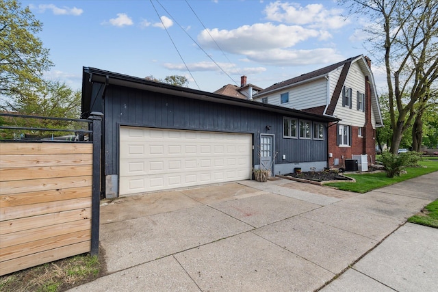 view of side of property featuring an attached garage, concrete driveway, brick siding, and central air condition unit
