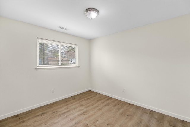 spare room with baseboards and light wood-type flooring