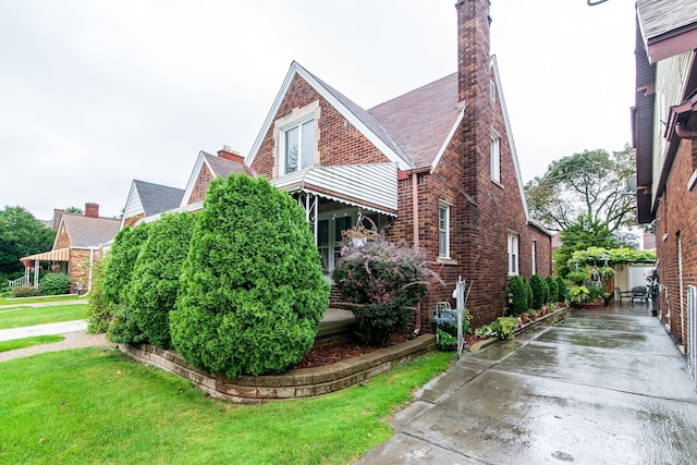 view of side of property featuring roof with shingles, brick siding, and a lawn