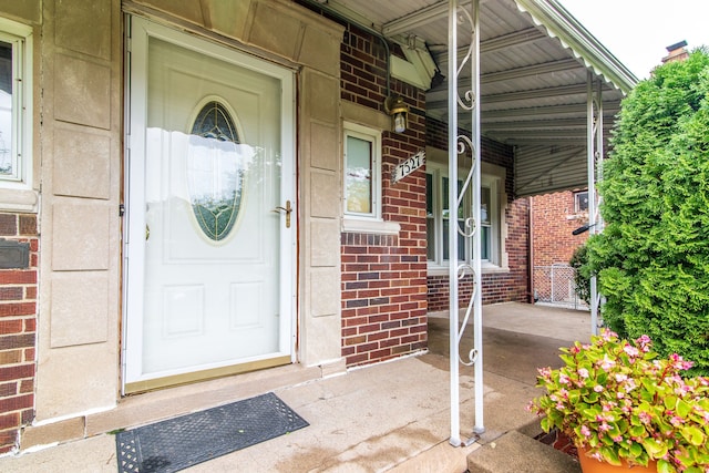 view of exterior entry featuring covered porch and brick siding