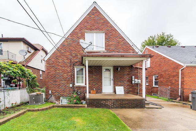 view of front of property featuring central air condition unit, brick siding, a front lawn, and fence