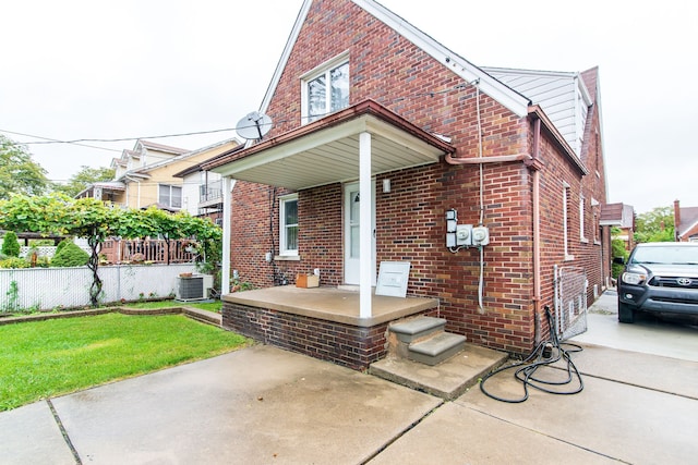 view of front of house with fence, brick siding, and central AC