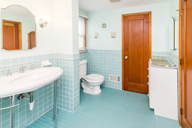 bathroom with tile walls, toilet, a wainscoted wall, visible vents, and tile patterned floors