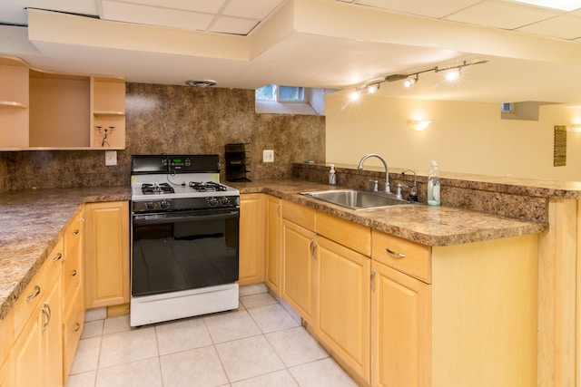 kitchen with a peninsula, light brown cabinetry, a sink, gas range oven, and tasteful backsplash