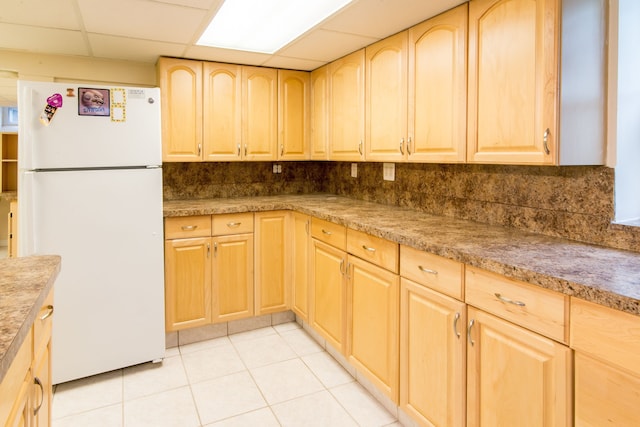kitchen with freestanding refrigerator, light brown cabinetry, a paneled ceiling, and light tile patterned floors