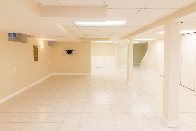 finished basement with baseboards, light tile patterned floors, and a drop ceiling