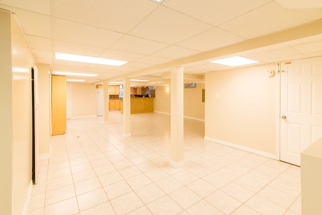 spare room with a drop ceiling, baseboards, and light tile patterned flooring