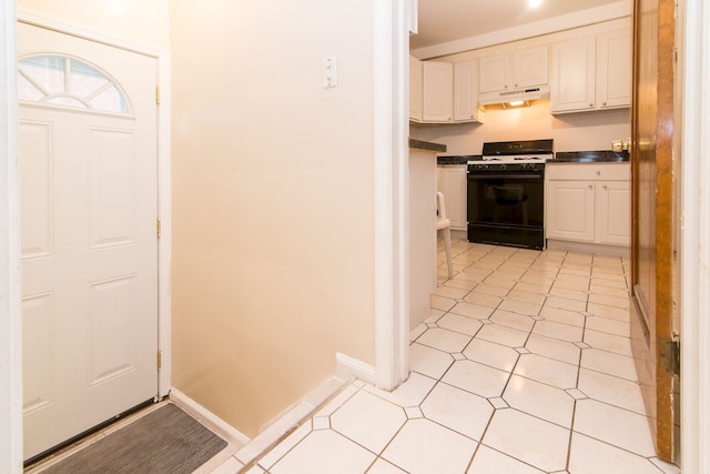 interior space with under cabinet range hood, range with gas cooktop, dark countertops, and white cabinets