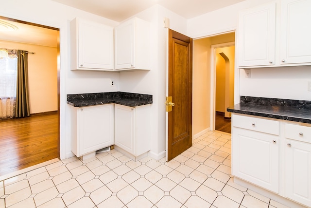 kitchen featuring white cabinets, baseboards, and arched walkways