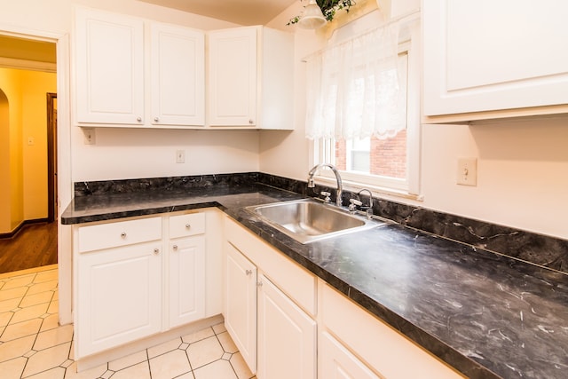 kitchen featuring white cabinets, arched walkways, and a sink