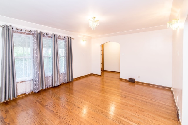 spare room featuring visible vents, wood finished floors, baseboards, and arched walkways