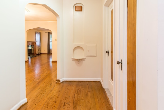 hallway with baseboards, arched walkways, and wood finished floors