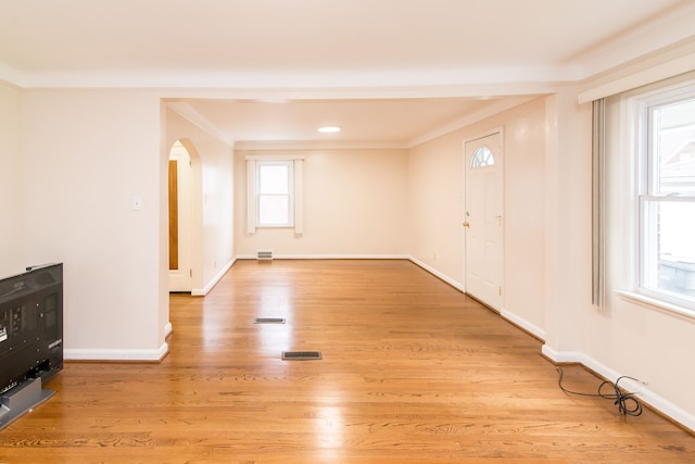 entrance foyer with light wood finished floors, arched walkways, baseboards, and visible vents