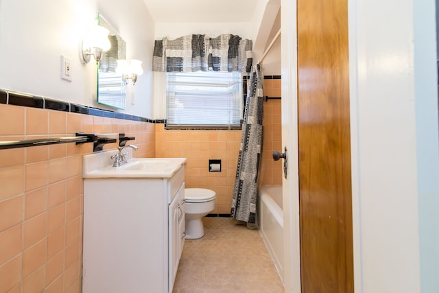 bathroom featuring tile walls, toilet, tile patterned flooring, vanity, and a wainscoted wall