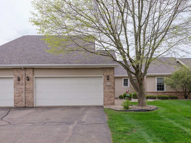 single story home with a front yard, roof with shingles, brick siding, and aphalt driveway