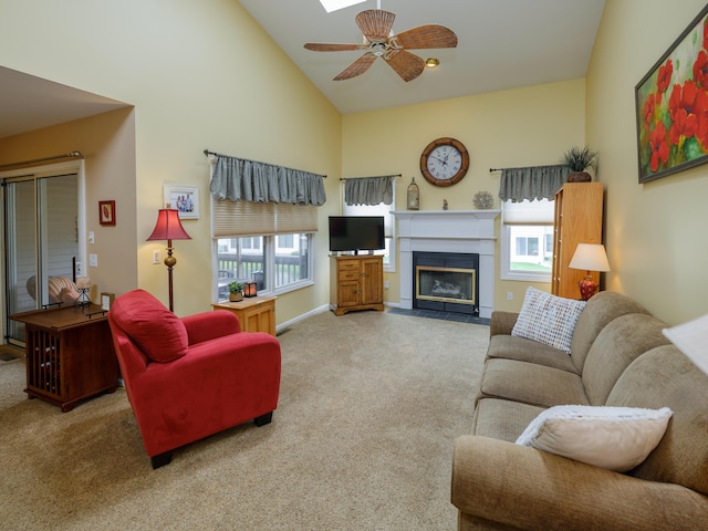 living area with a wealth of natural light, a ceiling fan, and carpet floors